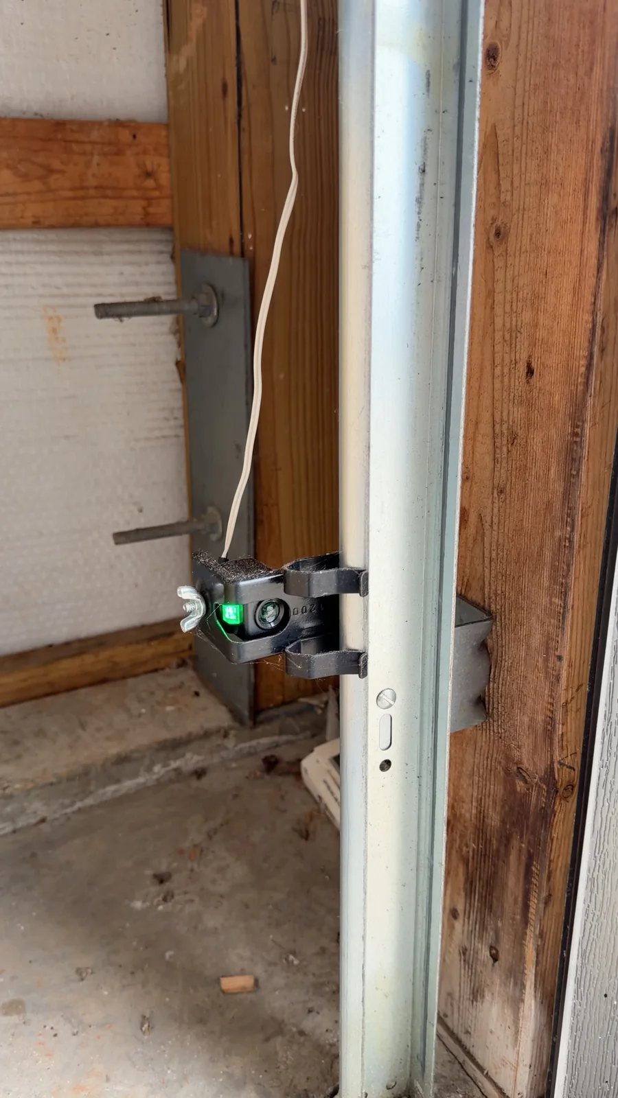 Close-up of a garage door safety sensor mounted on the door frame near the floor