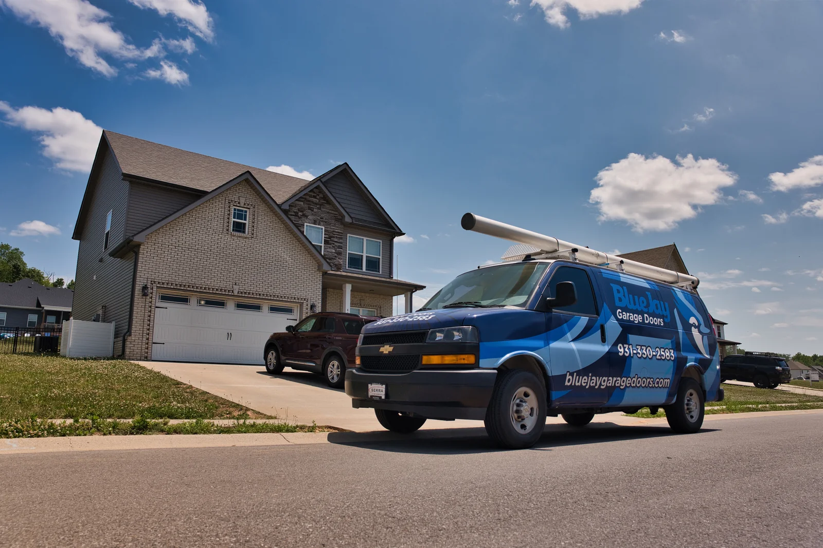 Blue Jay service van parked in front of a two-story home