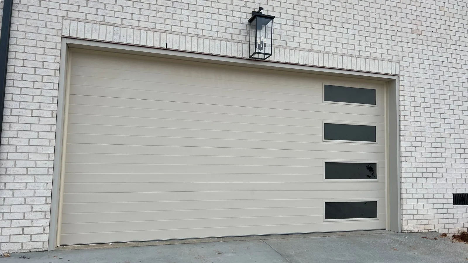 Light-colored modern garage door with a vertical row of side windows