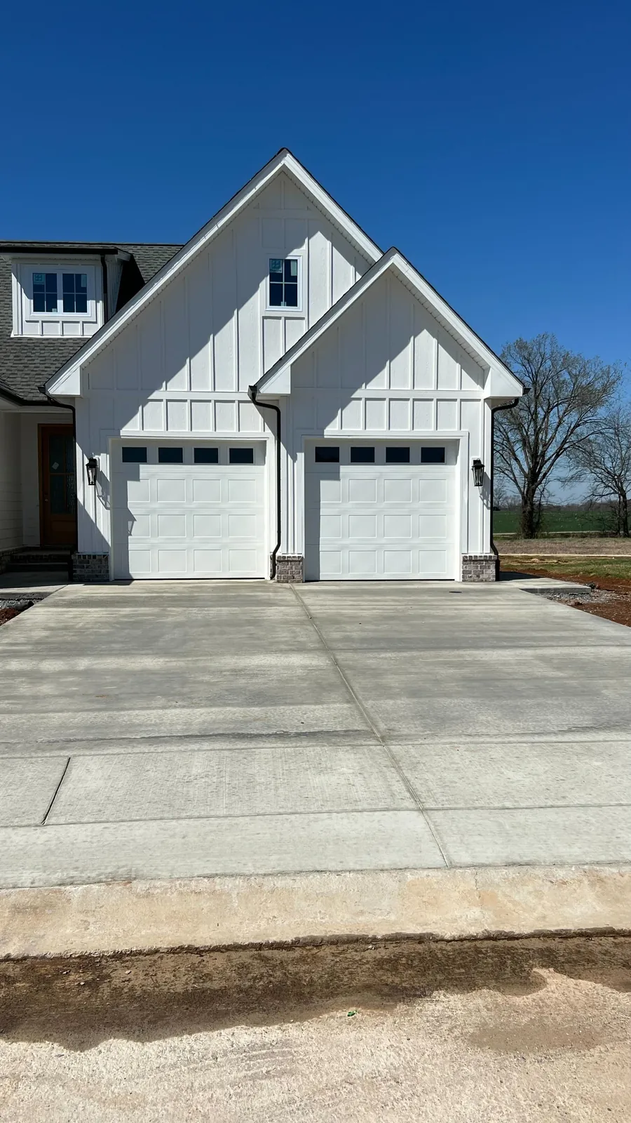 White garage doors beneath steep gables on a white home