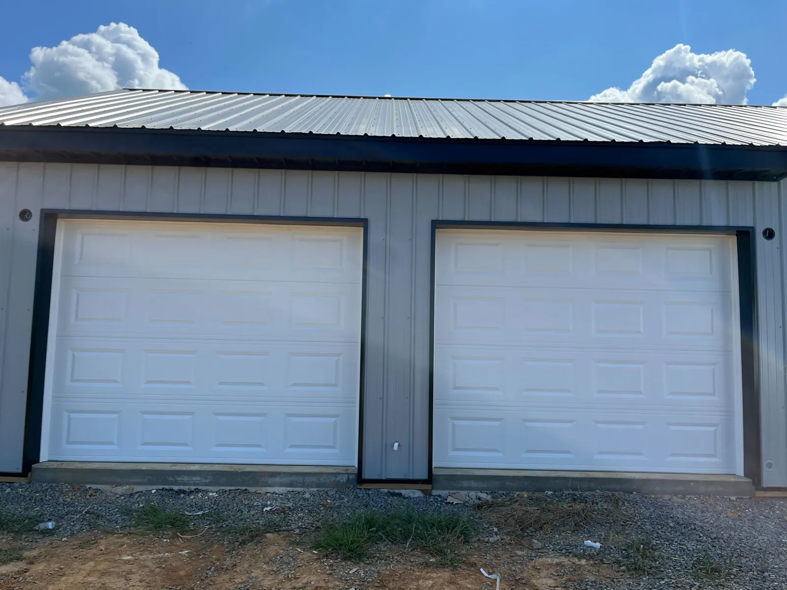 Two white raised-panel garage doors on a detached garage
