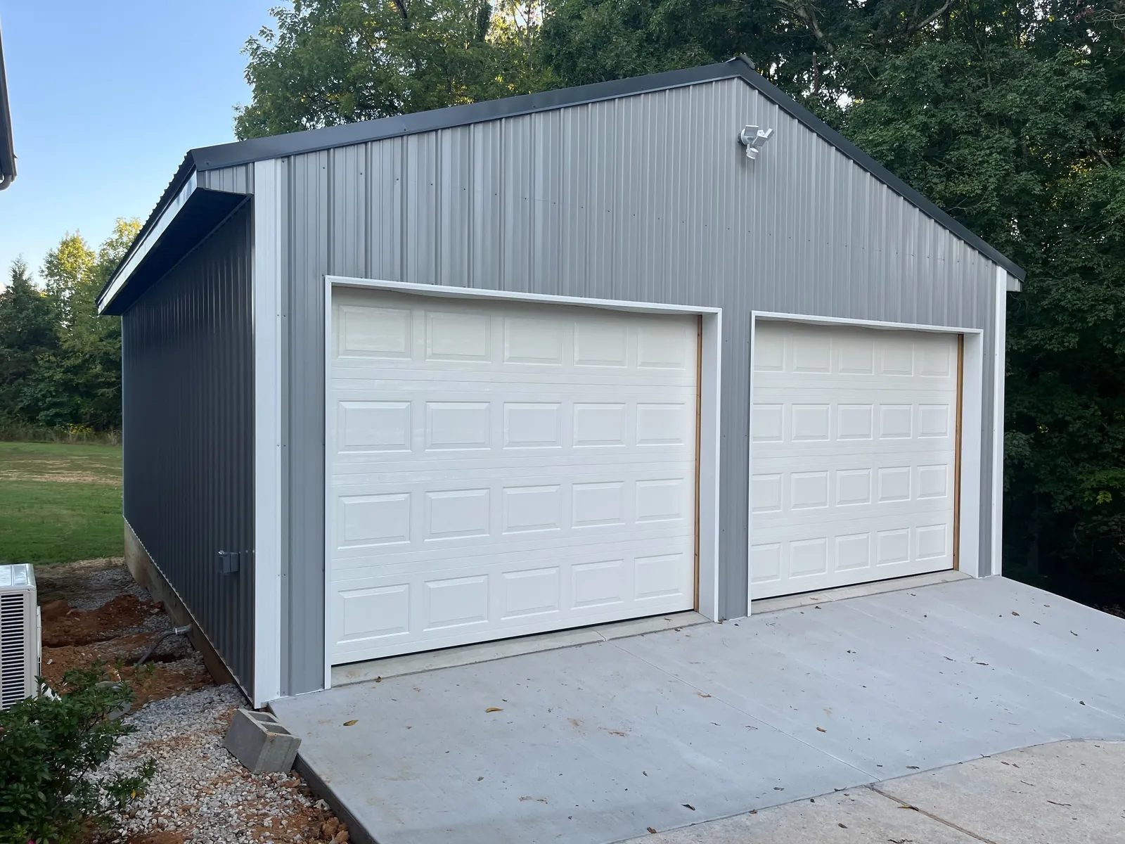 Two white garage doors on a gray detached garage