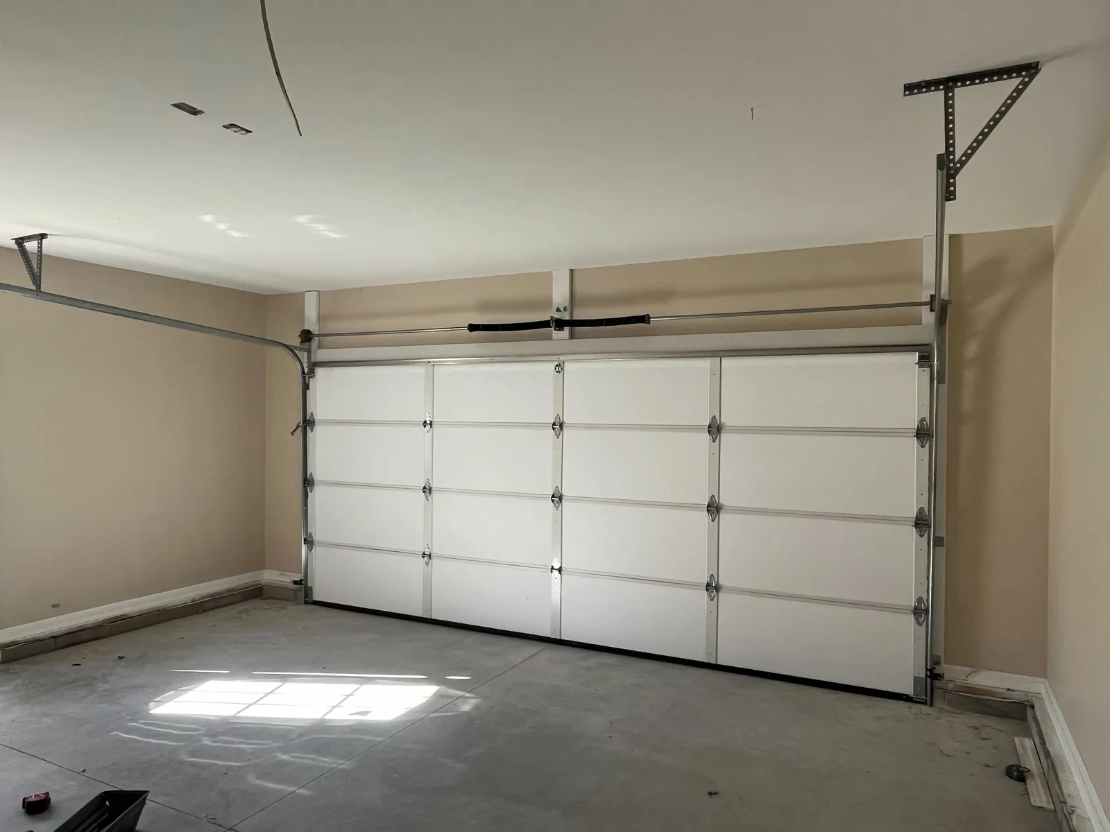 White sectional garage door and opener inside a finished garage