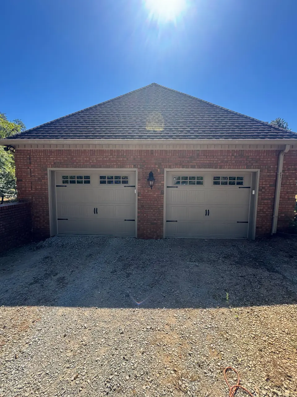Two tan carriage-style garage doors on a brick home