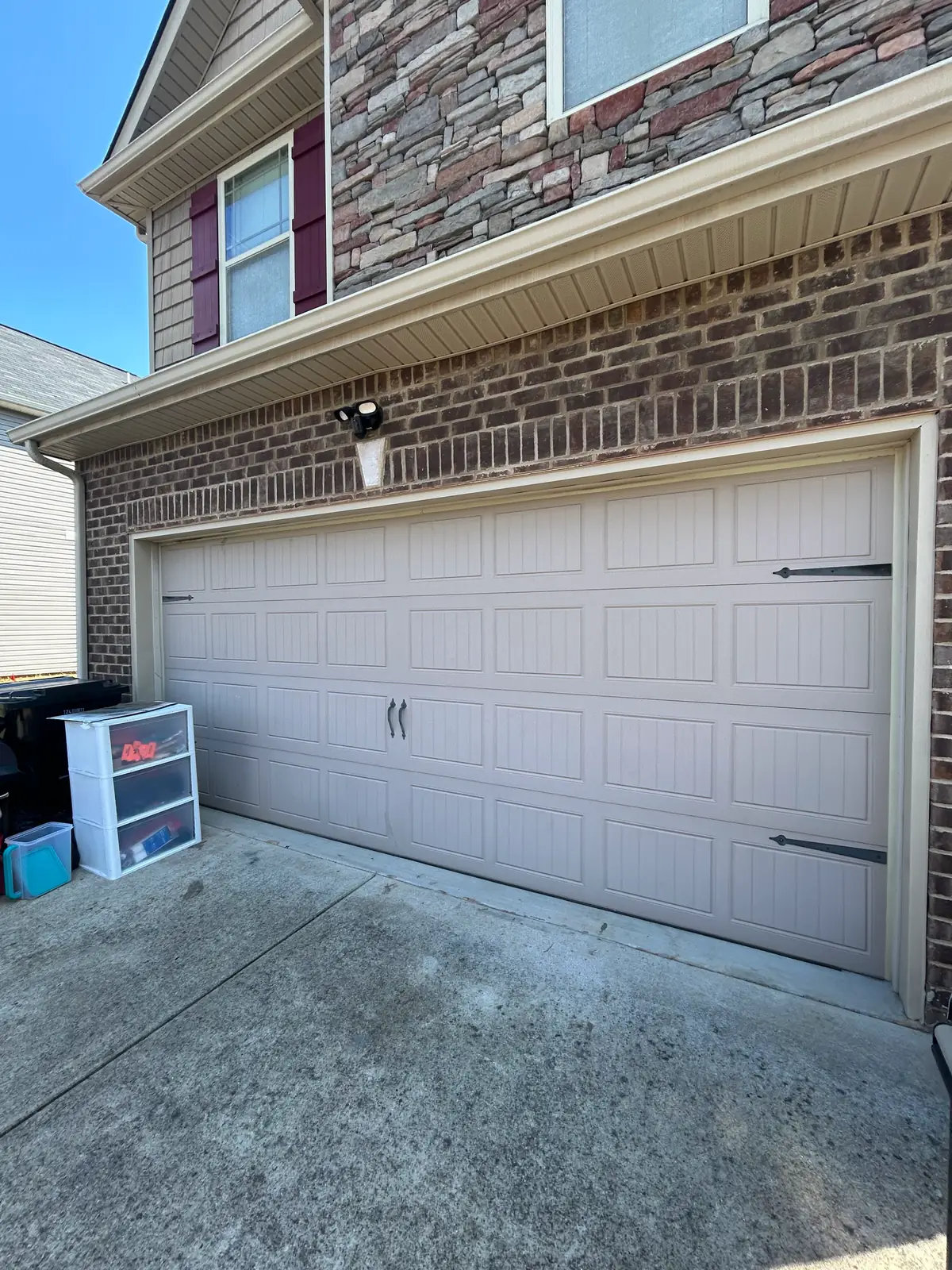 White carriage-style garage door with black decorative hardware on a brick home