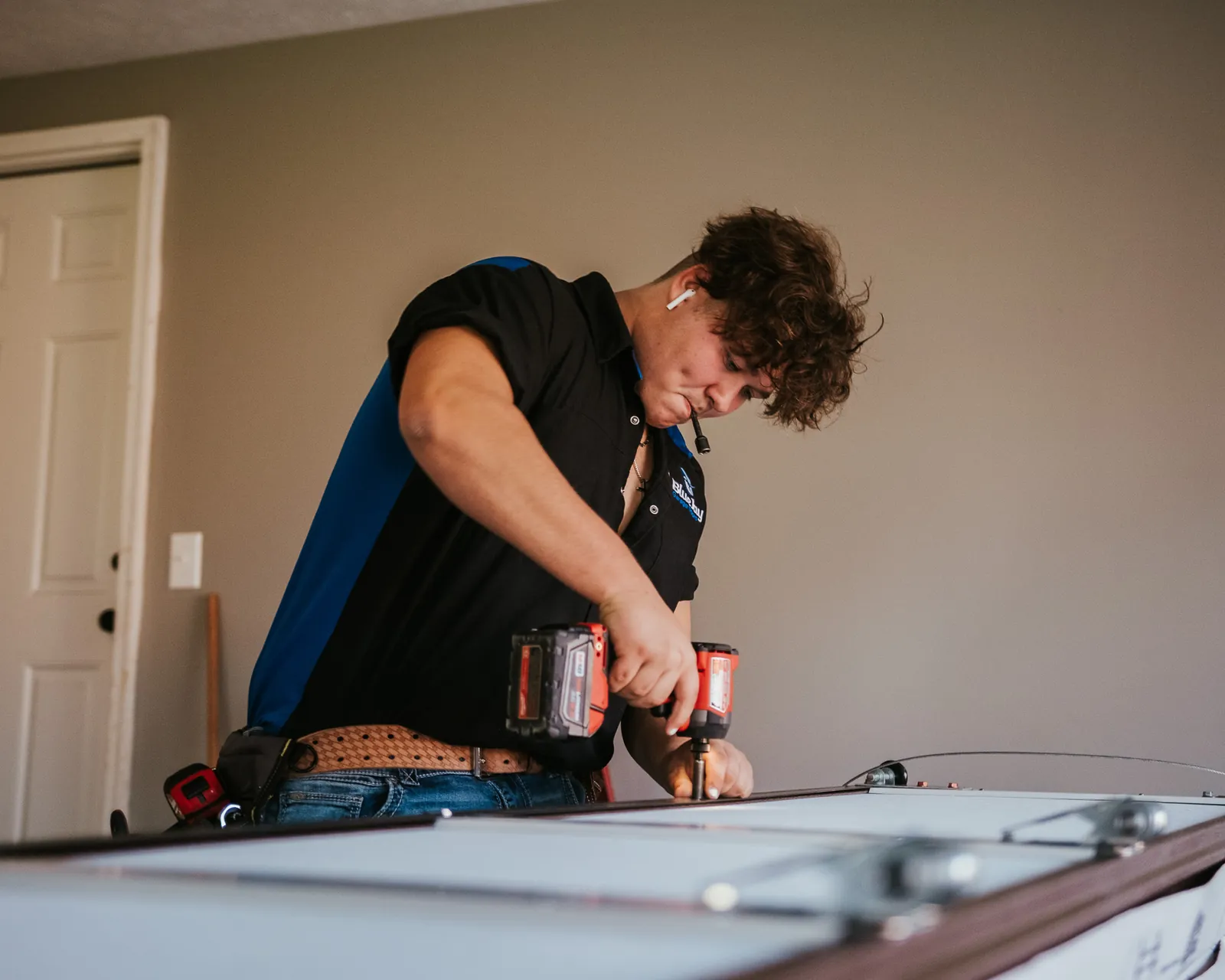 Blue Jay installer assembling garage door hardware with a cordless drill