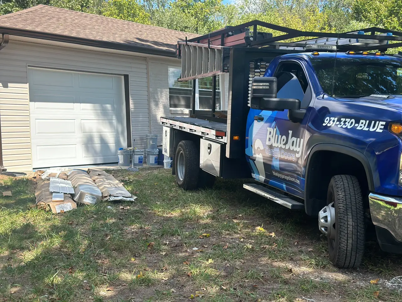Blue Jay work truck parked beside a residential garage