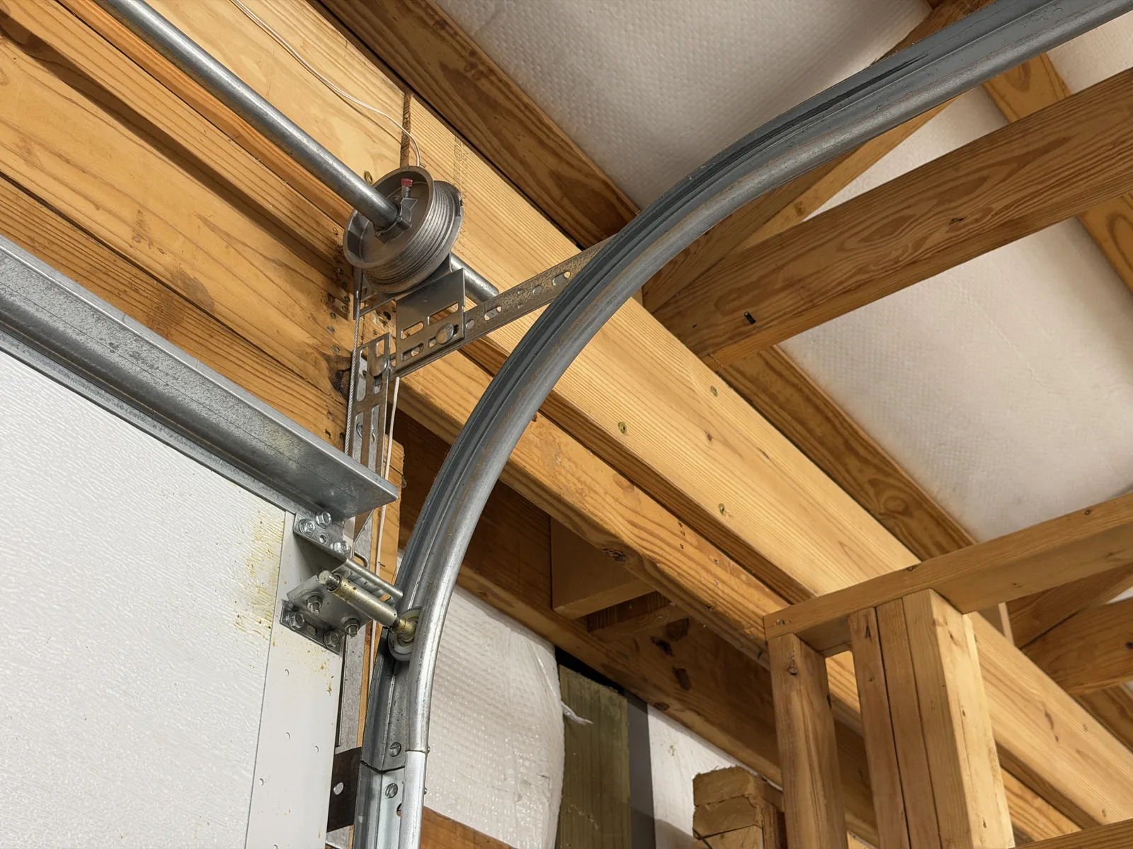 Cable drum and cable beside the upper corner of a garage door