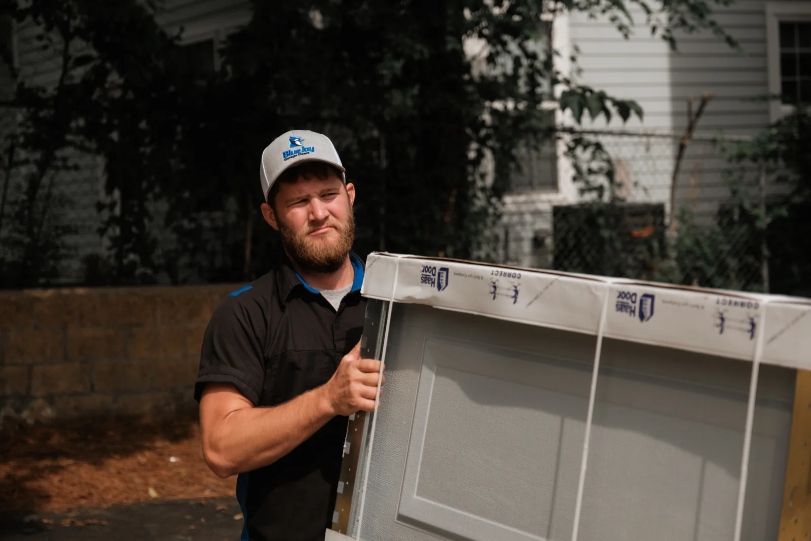 Blue Jay installer carrying a new garage door section