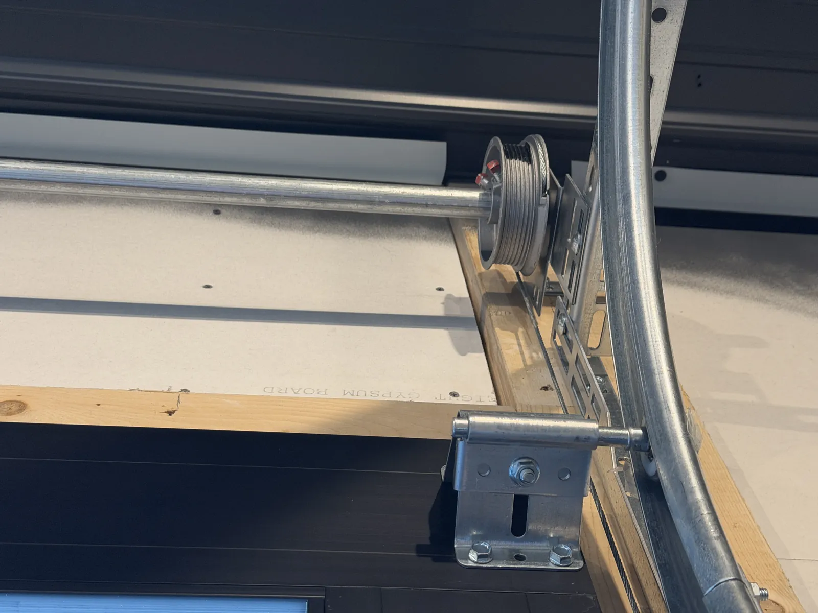 Garage door cable drum and mounting bracket above the door