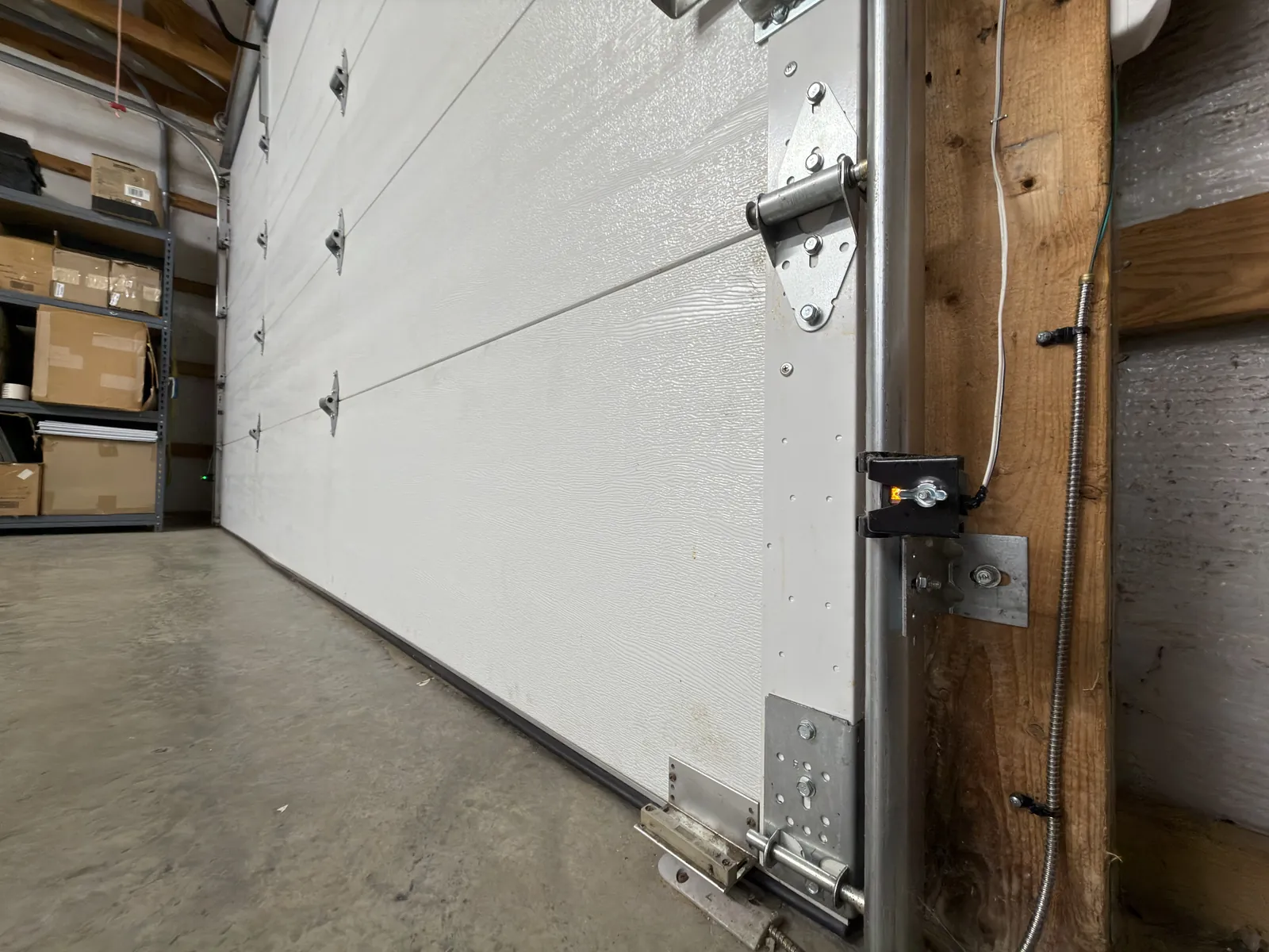 Garage door safety sensor mounted beside the bottom of a closed door