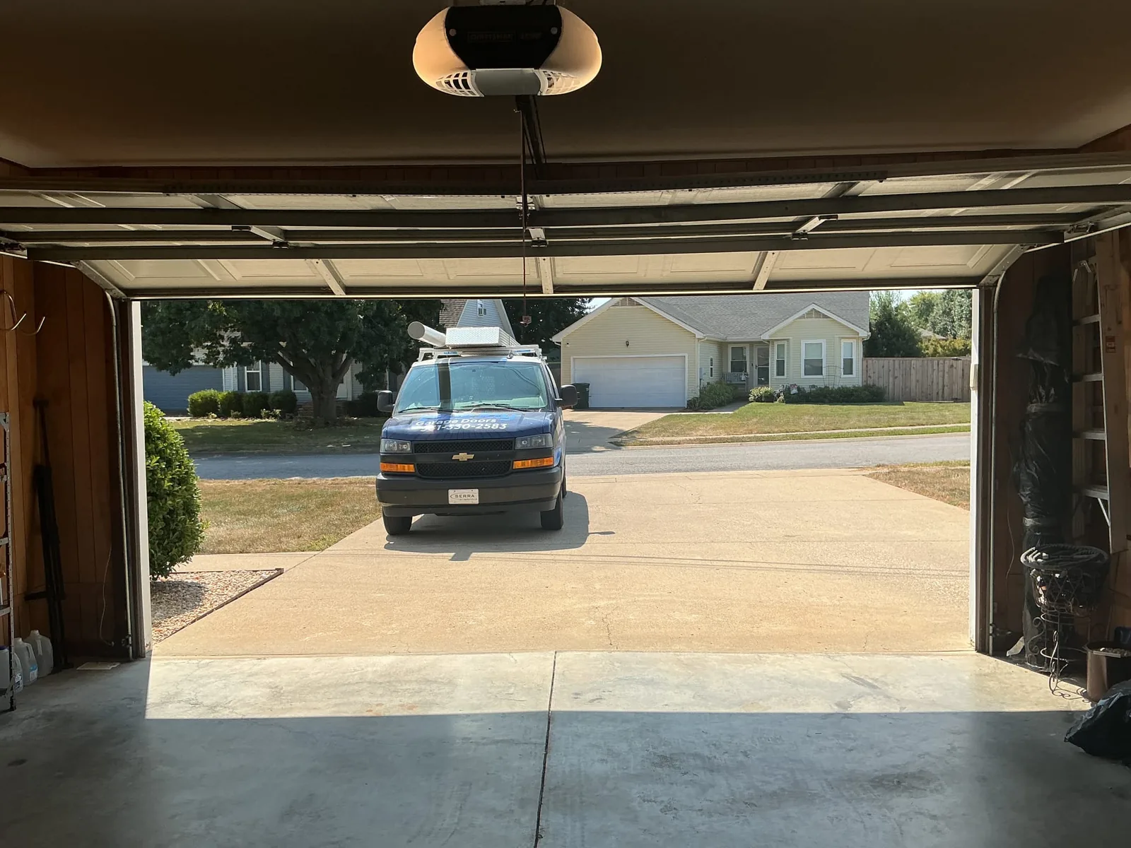 Open sectional garage door with a Blue Jay service van parked in the driveway