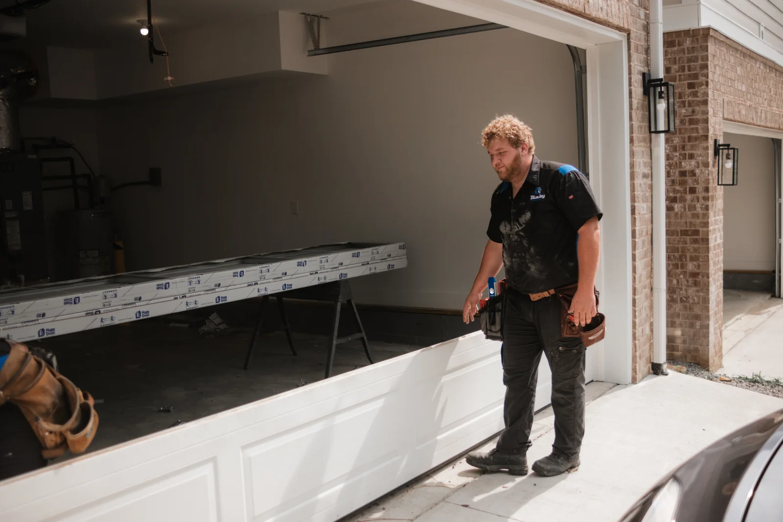 Blue Jay installer standing beside new garage door sections in an open garage