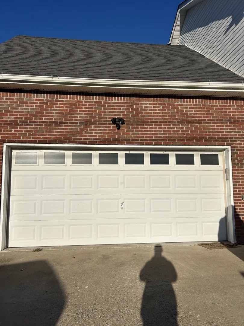 Cream garage door with top windows on a brick home before replacement