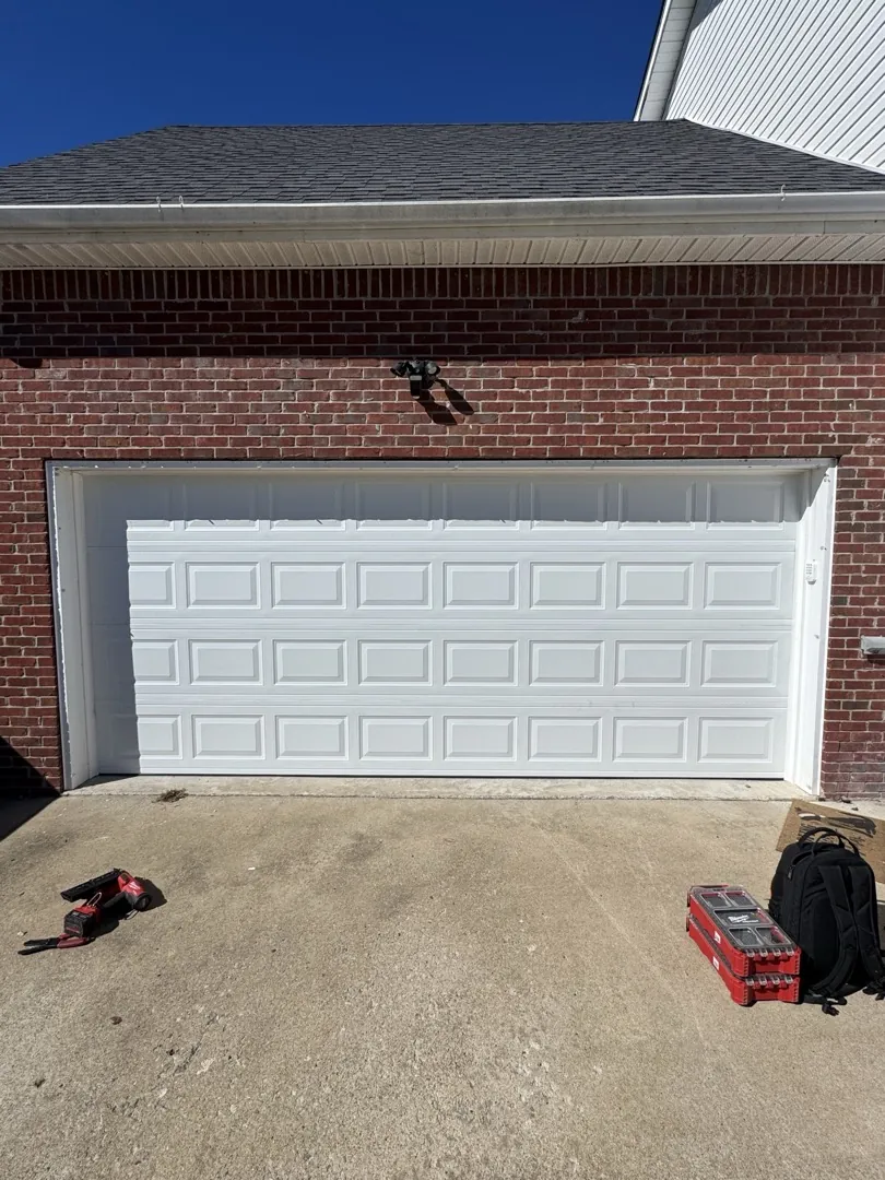 White raised-panel garage door on the same brick home after replacement