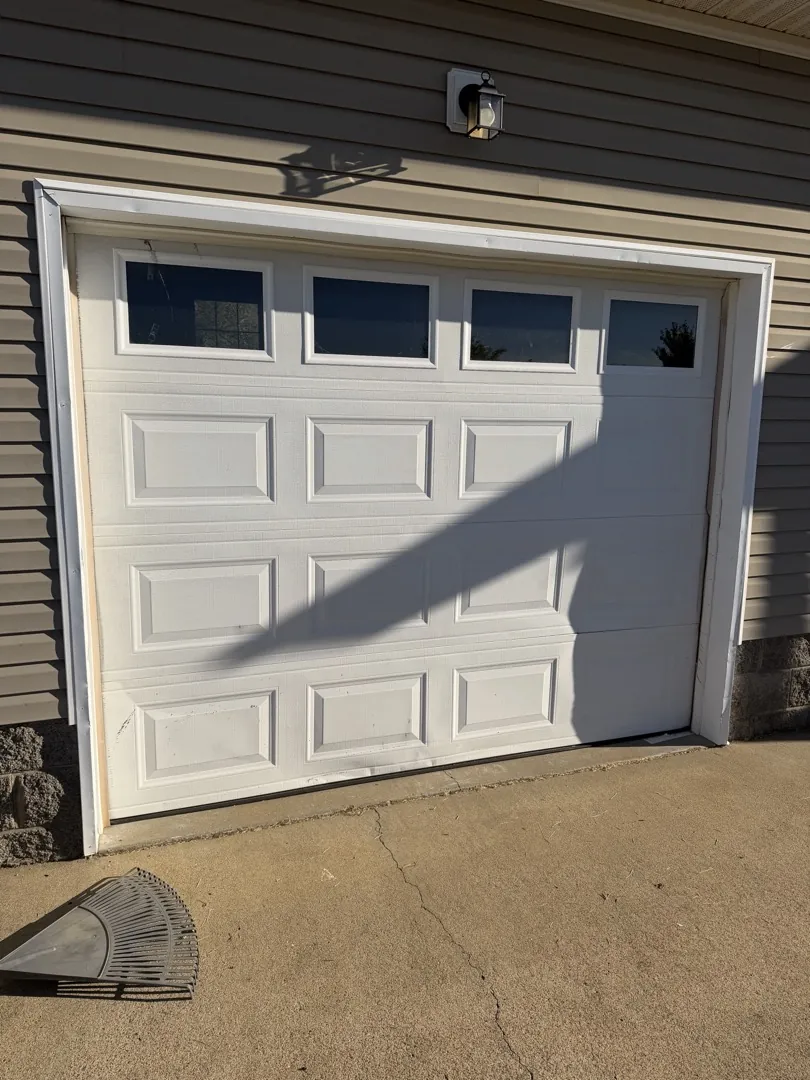 White garage door with top windows on a sided home before replacement