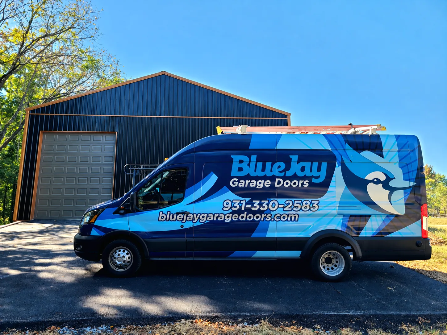 Blue Jay Garage Doors service van parked beside a blue garage building with a closed garage door