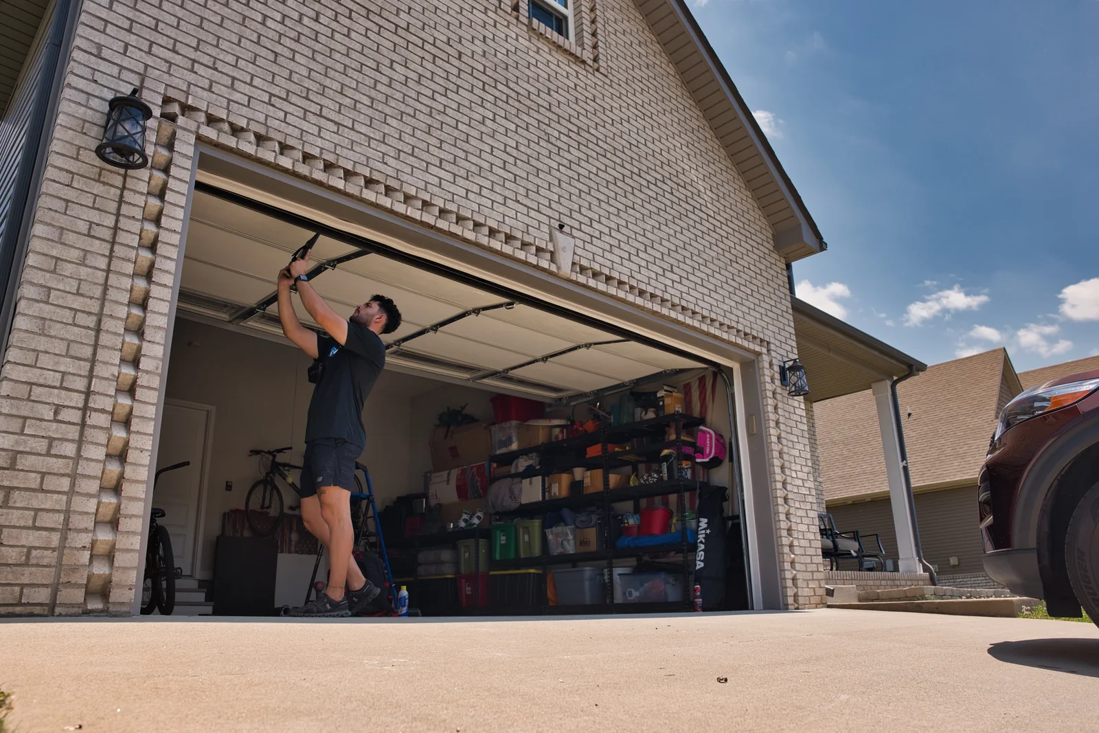 Blue Jay technician inspecting an open garage door on a brick home