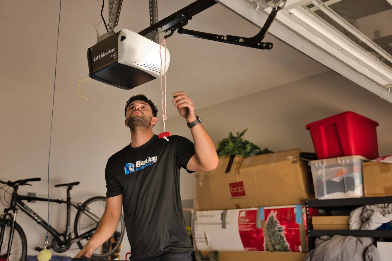 Blue Jay technician looking up at a garage door opener on the ceiling