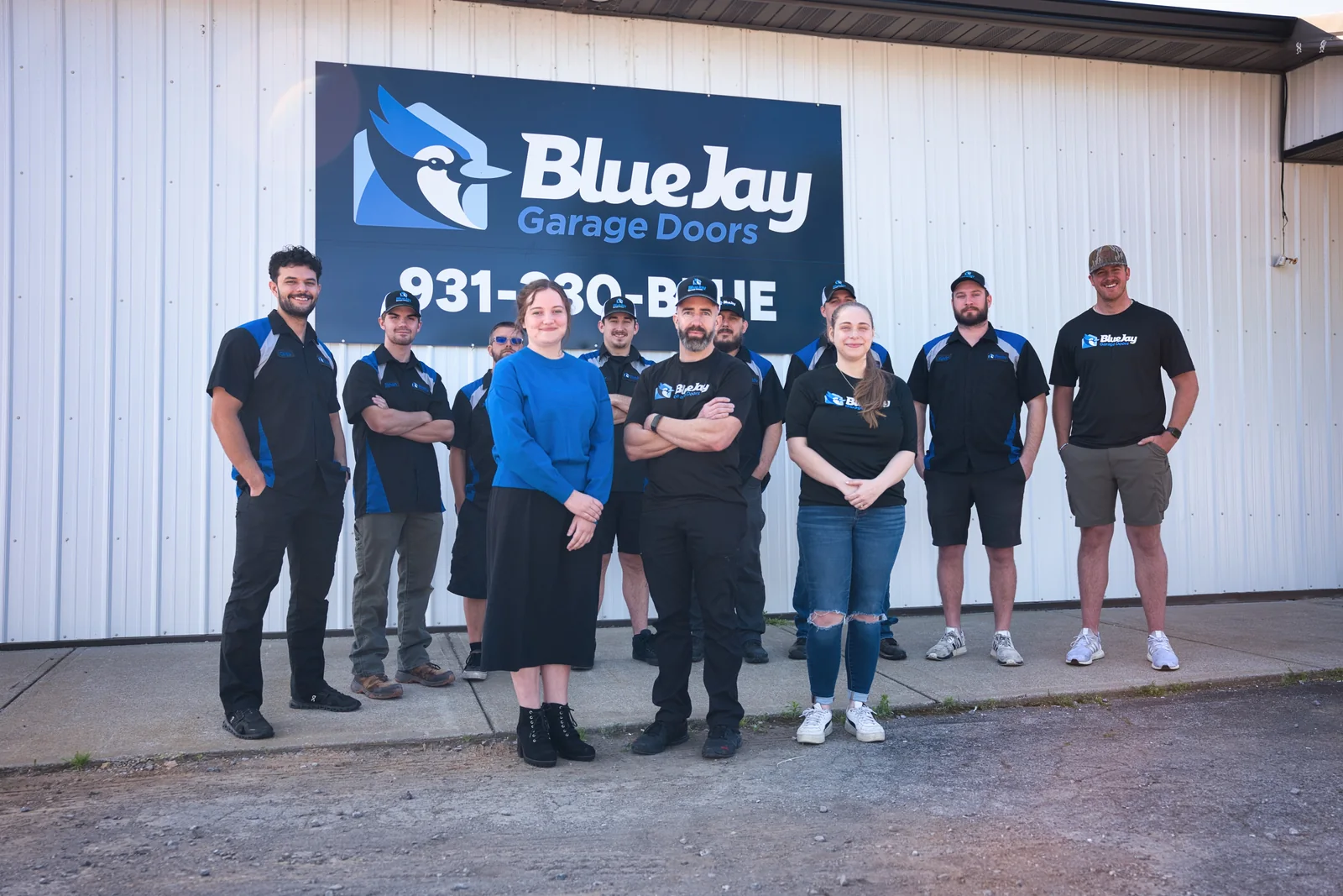 The Blue Jay Garage Doors team standing outside the company building under the Blue Jay sign