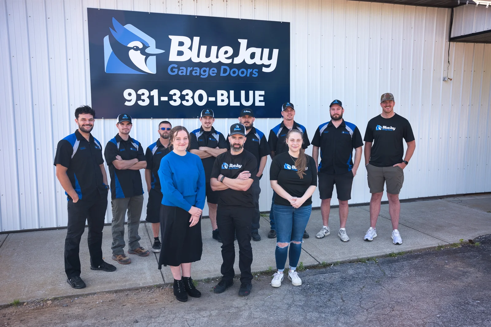 The Blue Jay Garage Doors team standing together in front of the Blue Jay sign