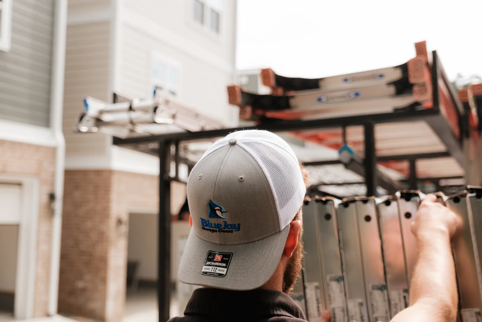 Blue Jay team member in a branded cap working at the ladder rack of a work truck