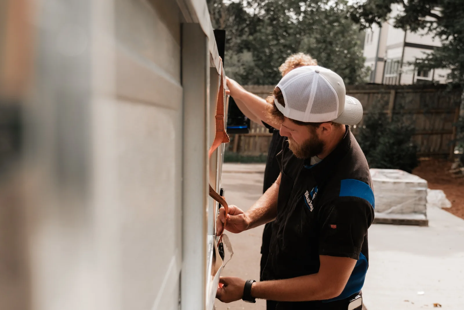 Blue Jay installers fitting hardware at the side of a garage door opening