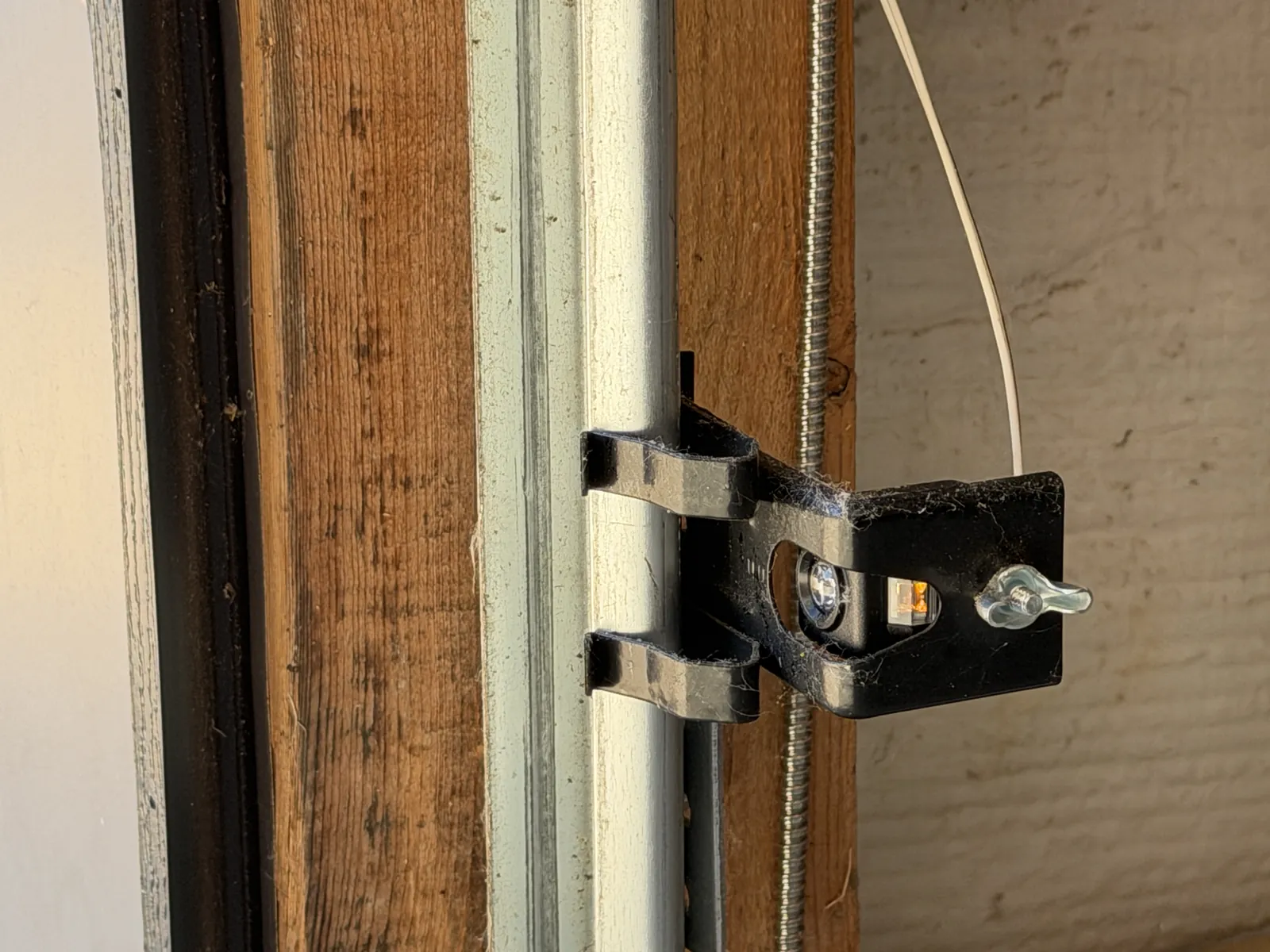 Close view of a garage door safety sensor mounted on a wooden jamb