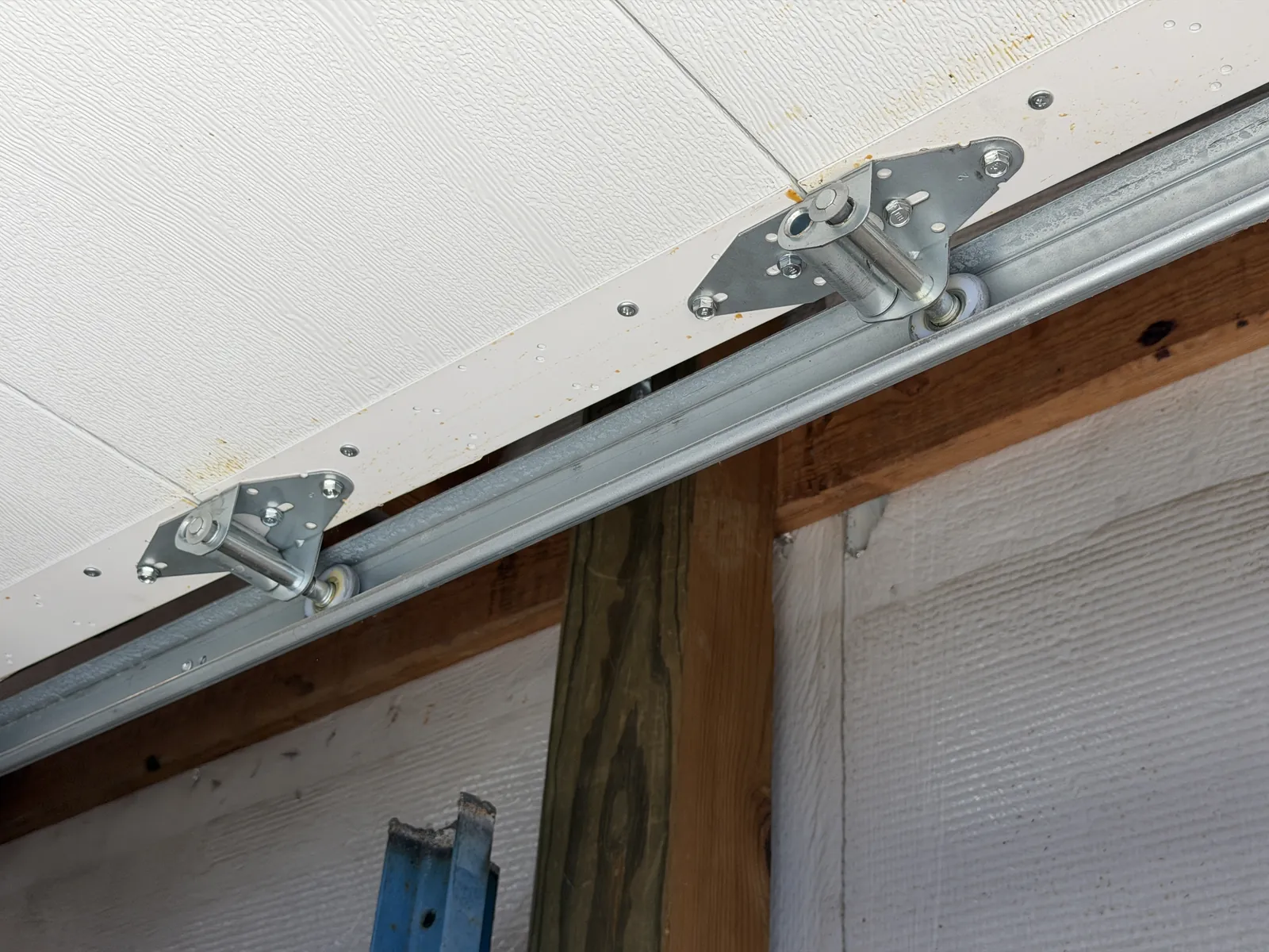Garage door rollers and hinges along a white sectional door