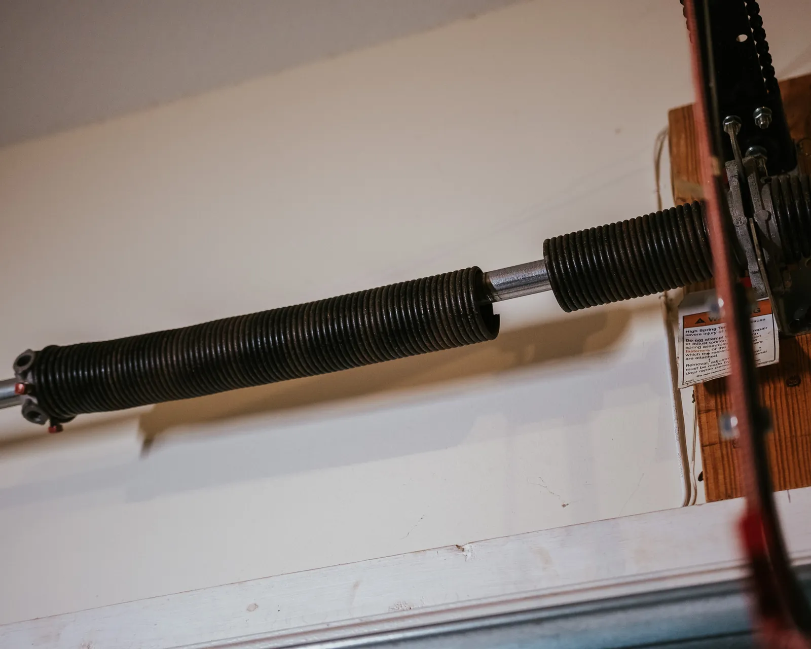 Broken torsion spring with a visible gap above a garage door