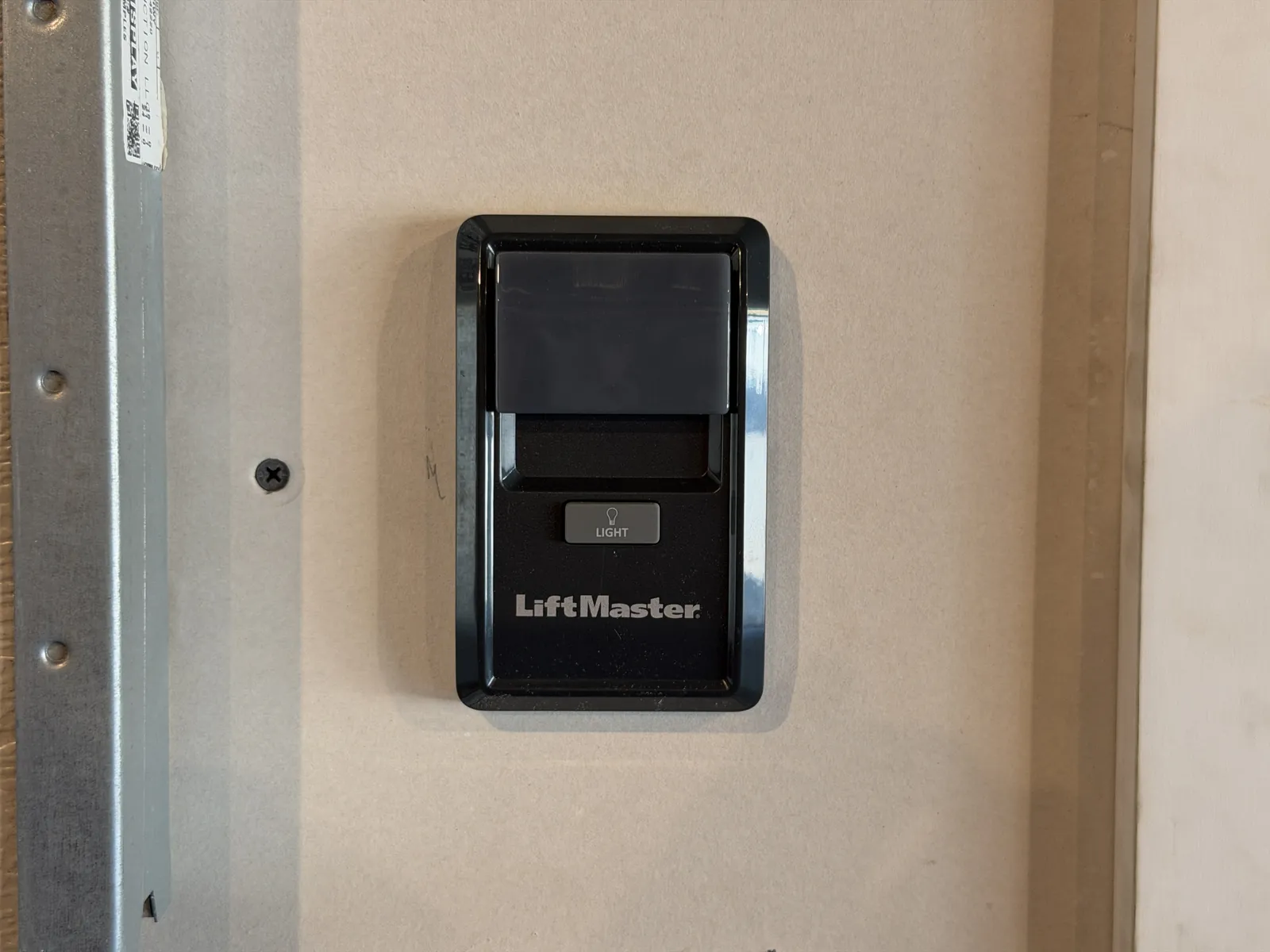 Black wall-mounted garage door control beside the door frame