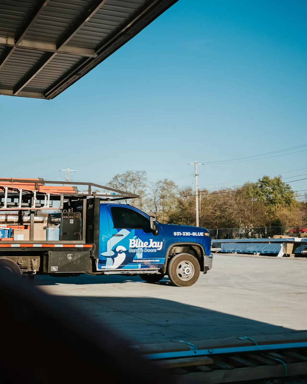 Blue Jay work truck parked beneath a roof overhang