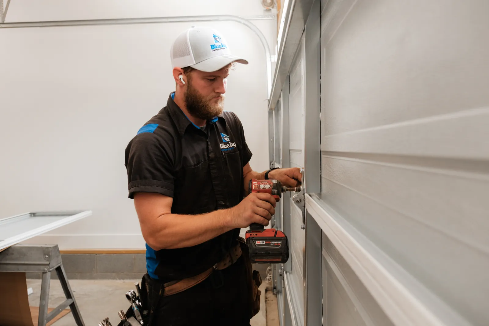 Blue Jay installer fastening hardware to a white garage door