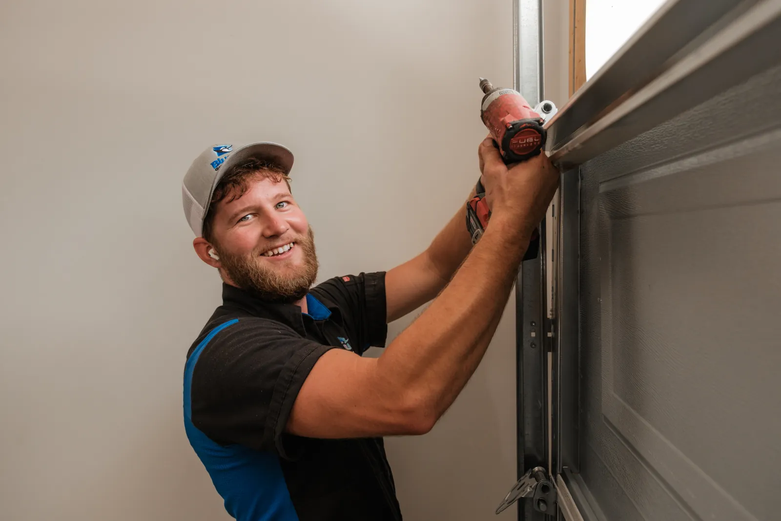 Blue Jay installer fitting hardware to a dark garage door