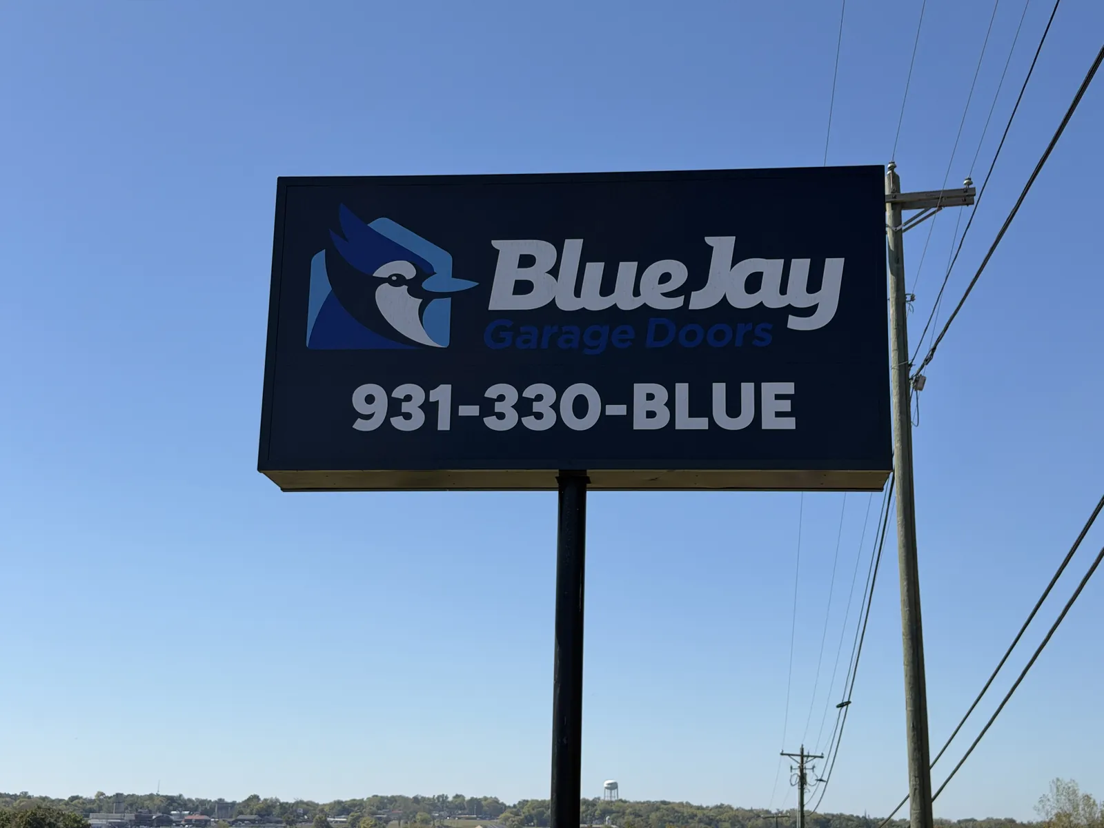 Blue Jay Garage Doors roadside sign against a blue sky