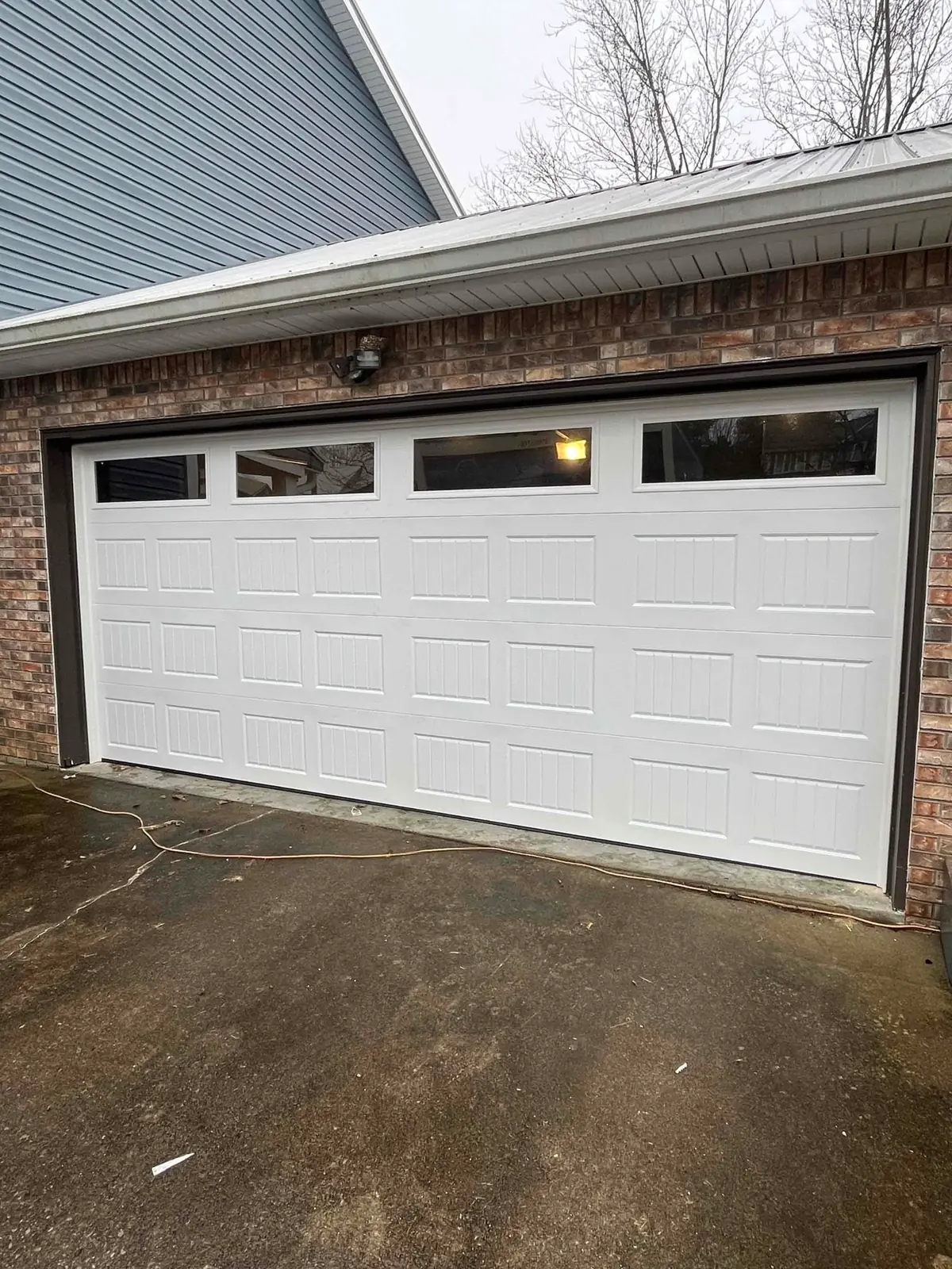 White garage door with top windows beside a brick exterior wall