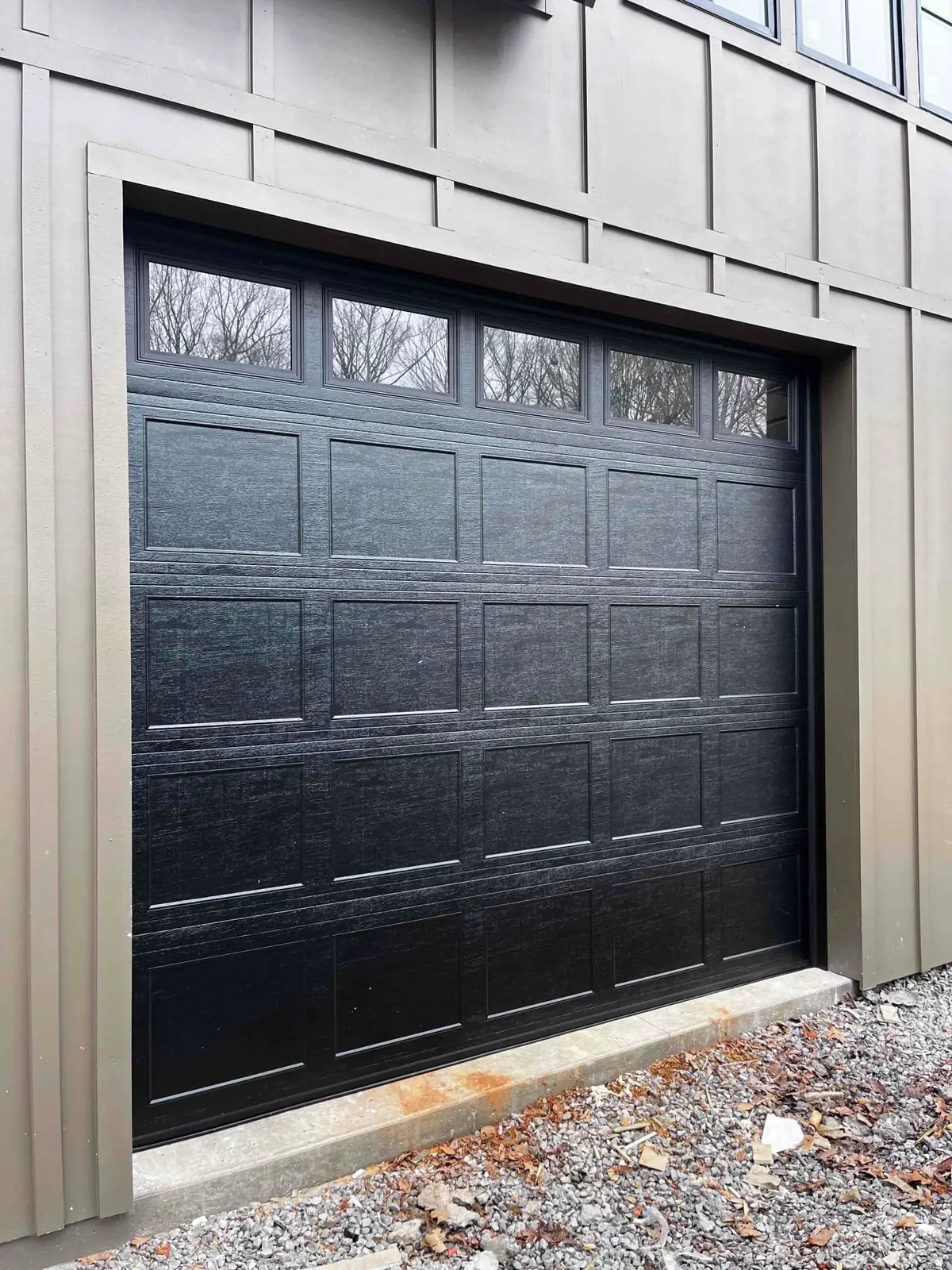 Close view of a dark garage door with decorative top windows
