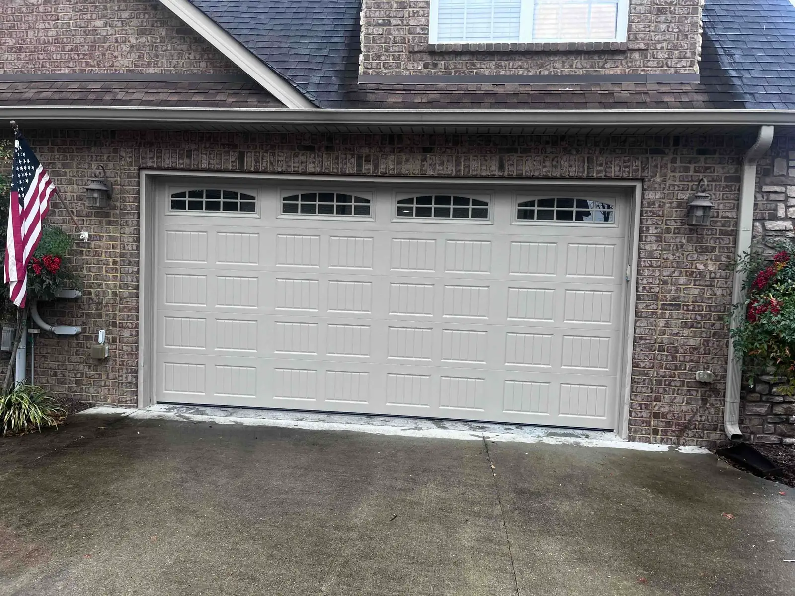 Cream carriage-style garage door with decorative hardware and top windows
