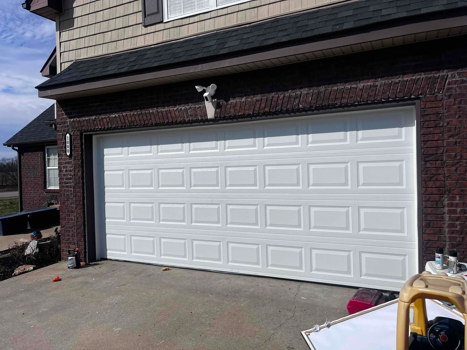 White raised-panel garage door on a brick home