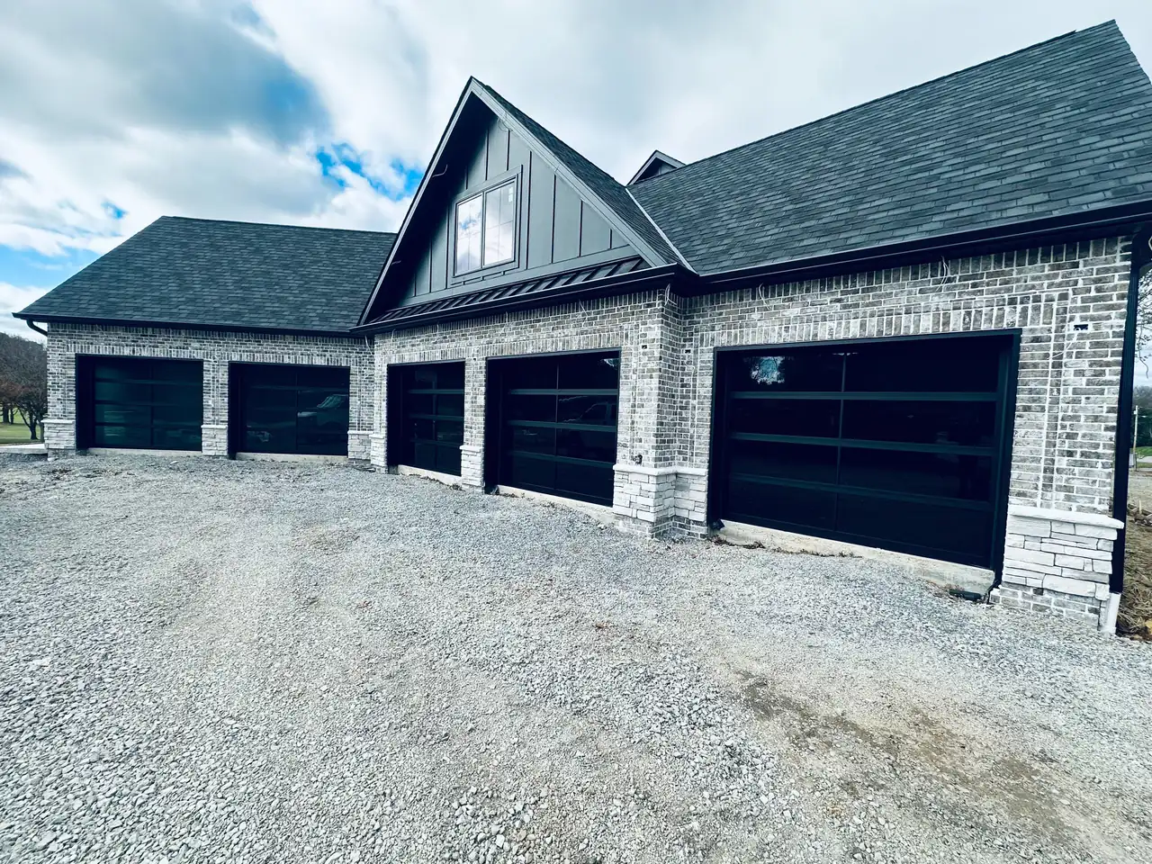 Dark garage doors with horizontal window panels on a white brick home