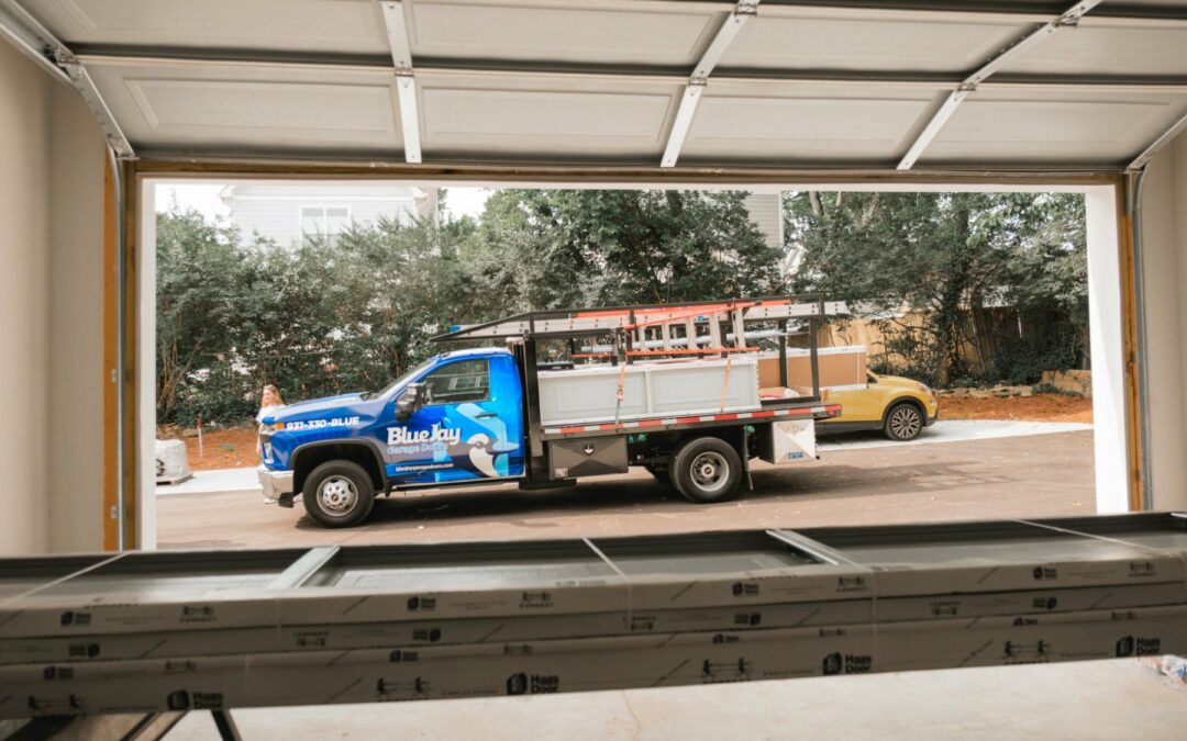 Blue Jay Garage Doors service truck outside of an open garage that is getting a new garage door installed