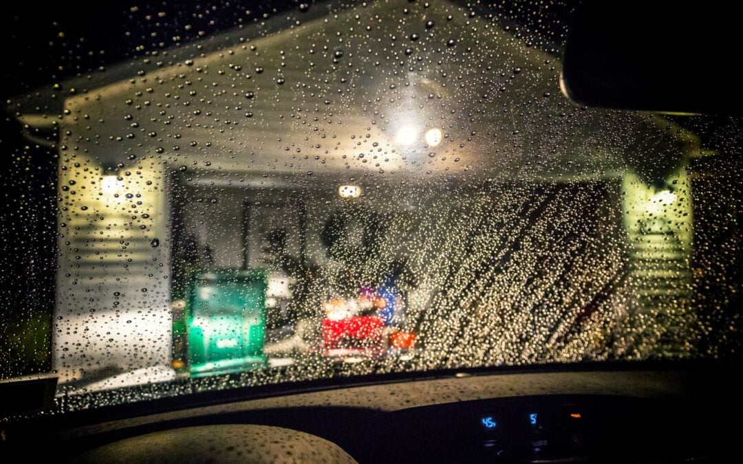 car approaching garage door at night during the rain