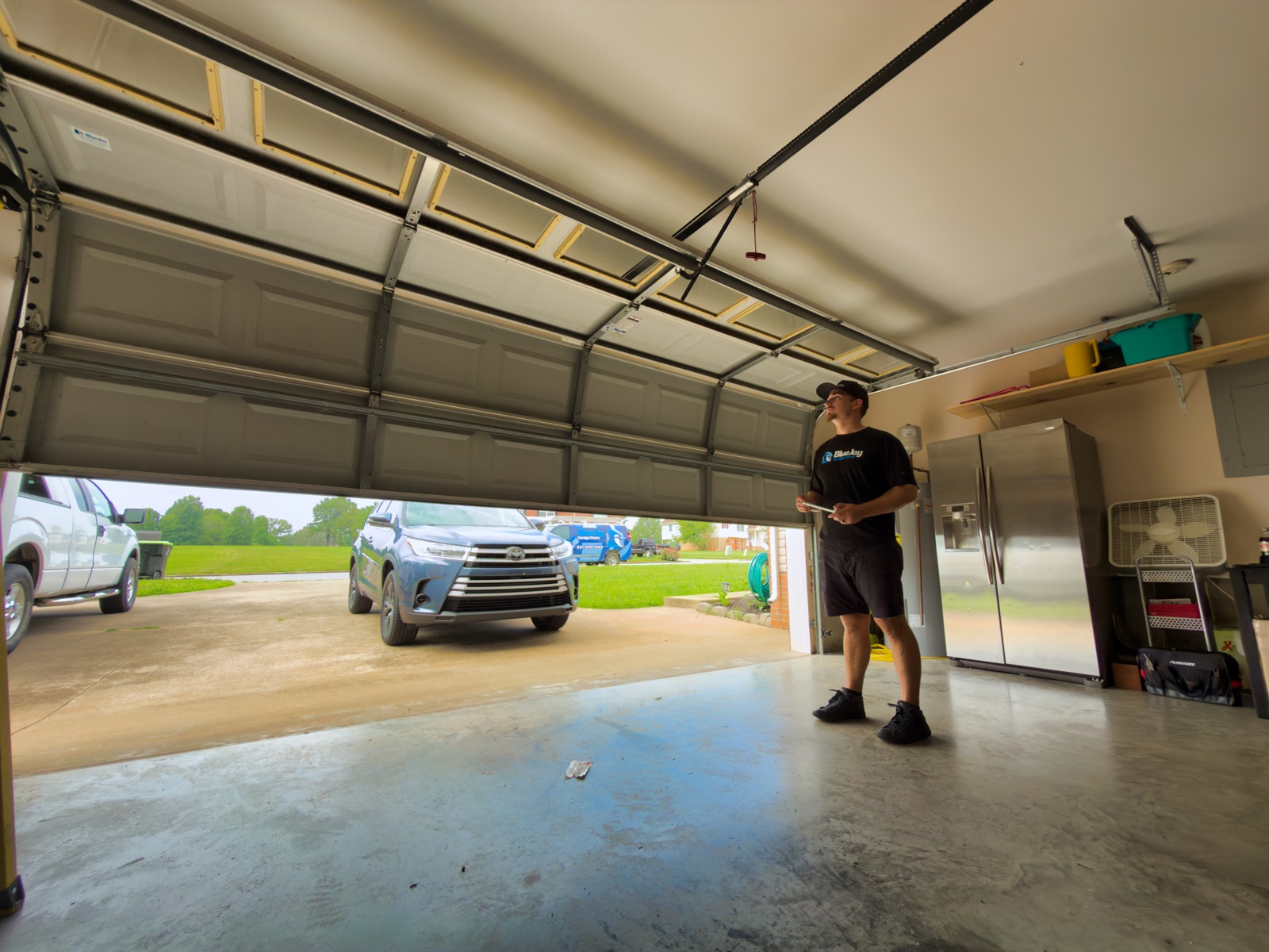 How Much Does a New Garage Door Cost in Clarksville, TN? Blue Jay technician inspecting a garage door spring system
