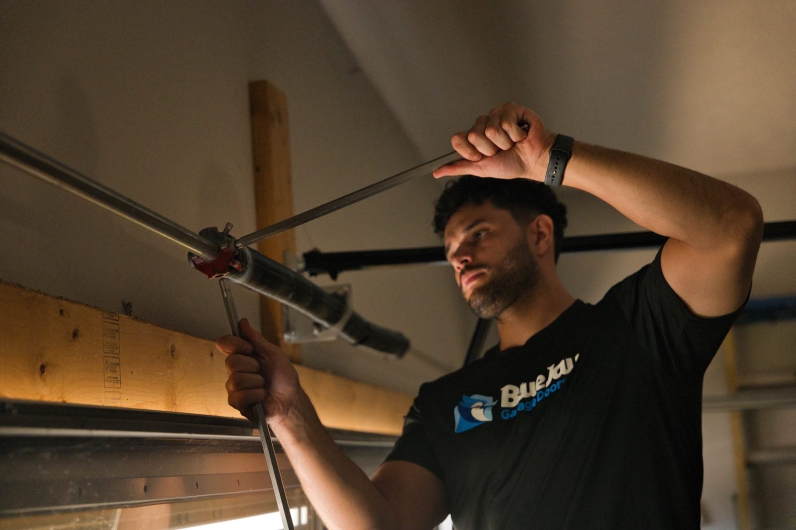 Garage Door Spring Broke in Clarksville? Here Is What Happens Next Blue Jay Garage Doors technician installing a torsion spring above a garage door